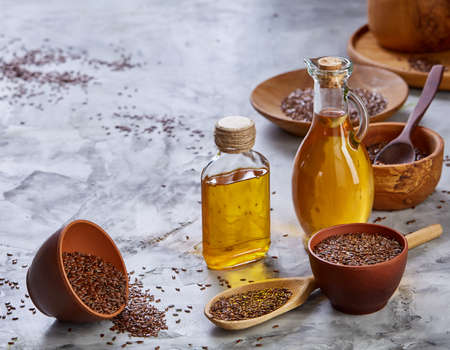 Flax seeds in bowl and flaxseed oil in glass bottle on wooden background, top view, close-up, selective focusの写真素材