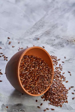 An overturned ceramic bowl with linseeds on a rustic background, close-up, shallow depth of field, selective focusの写真素材
