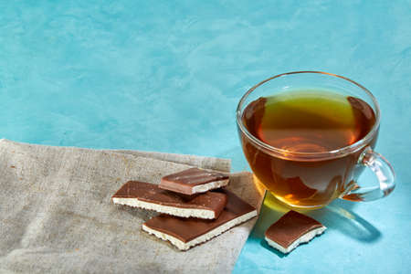 Glass cup of tea and chocolate cookies close-up on blue background.の写真素材