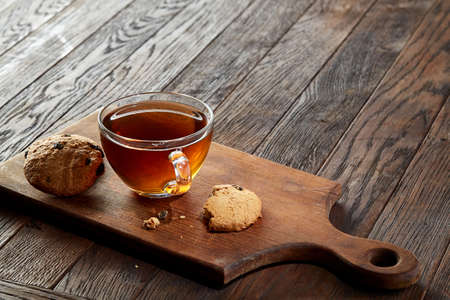 Cup of tea with cookies on a cutting board on a wooden background, top viewの写真素材