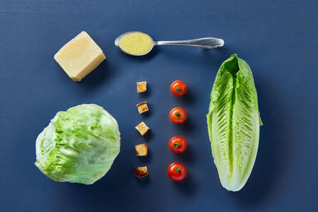 Yummy top view composition of fresh healthy salad ingredients on dark background.