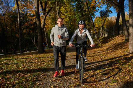 Happy young couple going for a bike ride on an autumn day in the park.の写真素材