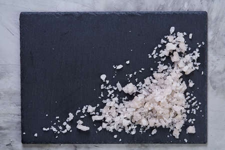 Pile of salt crystals over the dark board on white background, close-up, top view, macro, selective focusの写真素材