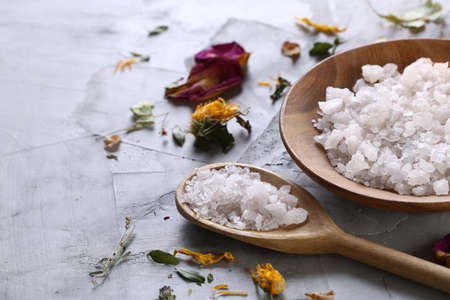 SPA concept: composition of spa treatment with natural sea salt, aromatic oil and flowers on white textured background, close up, top view, selective focus, shallow depth of field. Dayspa cosmetics products. Spa natural concept. Wellness setting.の写真素材