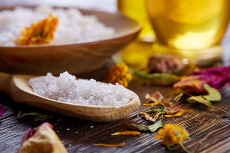 Composition of spa treatment on wooden background. Sea salt and flowers background, close up, top view, selective focus.の写真素材