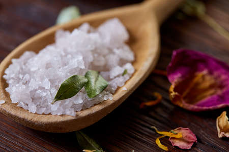 Composition of spa treatment on wooden background. Sea salt and flowers background, close up, top view, selective focus.の写真素材