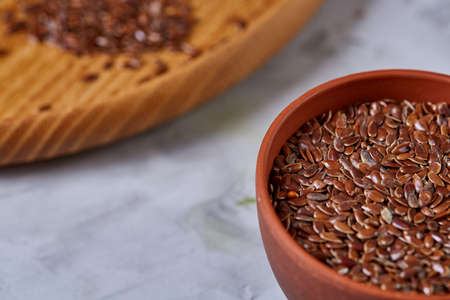 Flax seeds in bowl and flaxseed oil in glass bottle on light textured background, top view, close-up, selective focusの写真素材