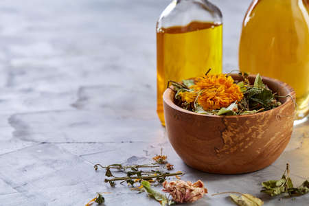 Spa still life with flowers in bowl and oil jars on light textured background, top view, close-up, selective focusの写真素材