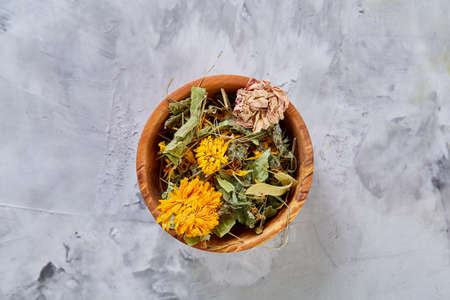 Spa still life with flowers in wooden bowl on light textured background, top view, close-up, selective focusの写真素材