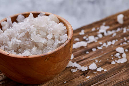 Large white sea salt in a natural wooden bowl on white background, top view, close-up, selective focusの写真素材