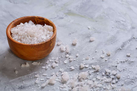 Large white sea salt in a natural wooden bowl on white background, top view, close-up, selective focusの写真素材
