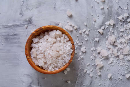 Large white sea salt in a natural wooden bowl on white background, top view, close-up, selective focusの写真素材