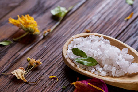 SPA concept: composition of spa treatment with natural sea salt, aromatic oil and flowers on wooden backgroundの写真素材