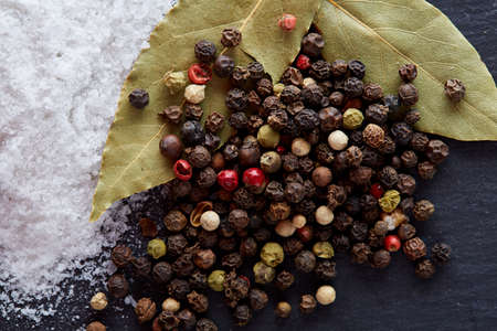 Composition of bay laurel leaf with peppercorn and salt isolated on dark background, top view, close-up, selective focusの写真素材