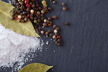 Composition of bay laurel leaf with peppercorn and salt isolated on dark background, top view, close-up, selective focusの写真素材