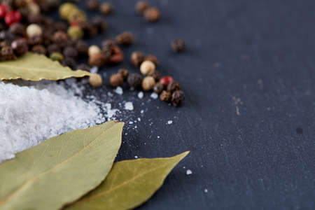 Composition of bay laurel leaf with peppercorn and salt isolated on dark background, top view, close-up, selective focusの写真素材