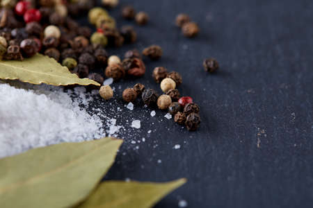 Composition of bay laurel leaf with peppercorn and salt isolated on dark background, top view, close-up, selective focusの写真素材