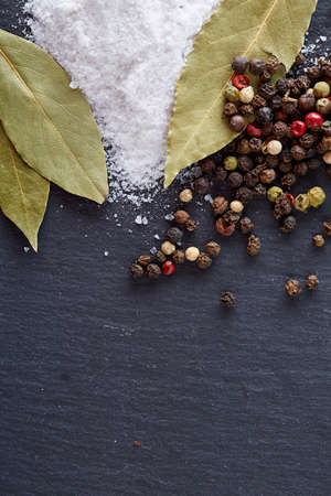 Composition of bay laurel leaf with peppercorn and salt isolated on dark background, top view, close-up, selective focusの写真素材