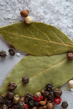 Composition of bay laurel leaf with peppercorn and salt isolated on dark background, top view, close-up, selective focusの写真素材