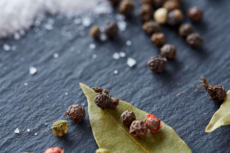 Composition of bay laurel leaf with peppercorn and salt isolated on dark background, top view, close-up, selective focusの写真素材