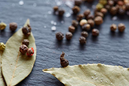 Composition of bay laurel leaf with peppercorn and salt isolated on dark background, top view, close-up, selective focusの写真素材