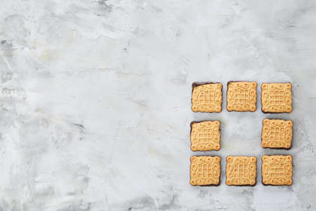 Square biscuits arranged in pattern on light textured background, close-up, shallow depth of field, selective focus.の写真素材