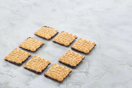 Square biscuits arranged in pattern on light textured background, close-up, shallow depth of field, selective focus.の写真素材