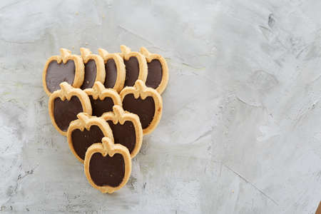 Apple shaped biscuits arranged in rows on light textured background, close-up, shallow depth of field, selective focus.の写真素材
