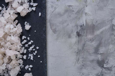 Pile of salt crystals over the dark board on white background, close-up, top view, macro, selective focusの写真素材