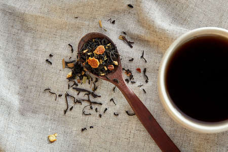 Ceramic cup of tea with scattered tea leaves on a napkin on rustic wooden background, selective focusの写真素材