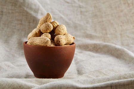 Unpeeled pistachios in ceramic bowl closeup, selective focusの写真素材