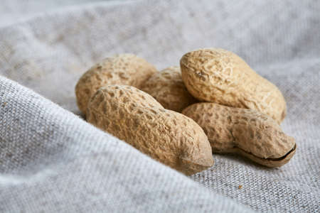 Heap of peanuts on light tablecloth, close-up, shallow depth of field, selective focus, macro