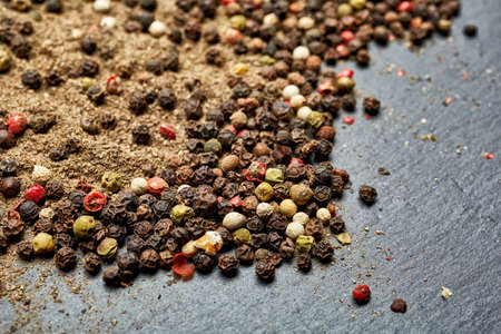 Mix of grind black pepper and black, white, red and yellow peppercorn. Selective focus.の写真素材