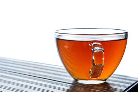 Close up picture of tea in transparent cup on dark table ove white background, shallow depth of field.の写真素材