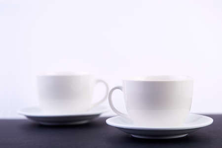 Two white porcelain teacups on black table show clean and simple design ideas, selective focusの写真素材