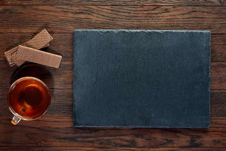 Cup of tea with a couple of chocolate waffles on a wooden background, top view, selective focusの写真素材