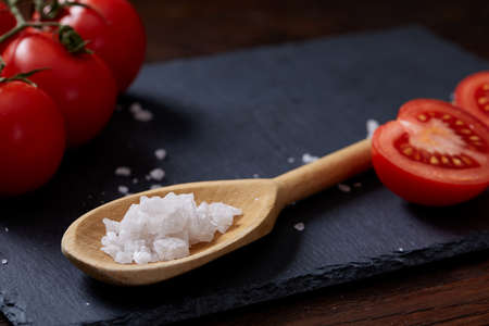 Vegetarian still life with fresh grape tomatoes, pepper and salt in wooden spoon on wooden background, selective focusの写真素材