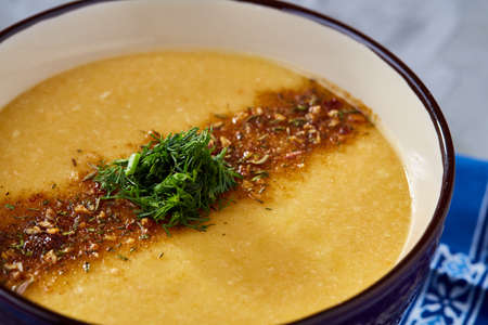 Porcelain bowl of pumpkin soup on napkin over white textured background, close-up, selective focus, top view.の写真素材
