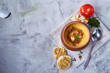 Clay pot of pumpkin soup on napkin over white textured background, close-up, selective focus, top view.の写真素材