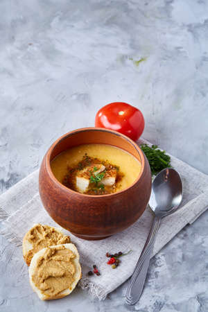 Clay pot of pumpkin soup on napkin over white textured background, close-up, selective focus, top view.の写真素材