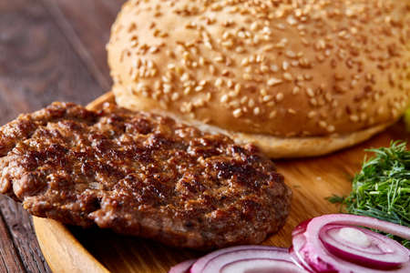 Yummy hamburger ingredients artistically organized on wooden plate, close-up, top view, selective focusの写真素材