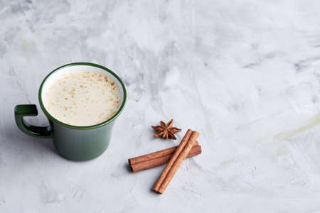 Cup of creamy coffee with cinnamon and star anise on a white textured background, top view, close-up, selective focusの写真素材