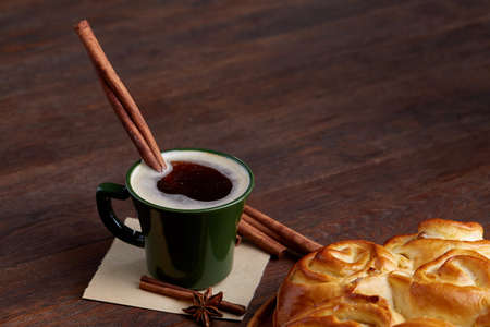 Creamy coffee in cup with homemade rose bread on vintage wooden background, close-up, selective focusの写真素材