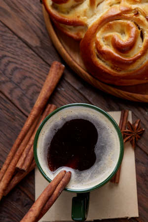 Creamy coffee in cup with homemade rose bread on vintage wooden background, close-up, selective focusの写真素材