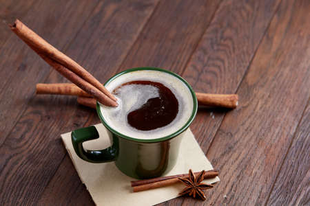 Cup of creamy coffee with cinnamon and star anise on a wooden table, top view, close-up, selective focusの写真素材