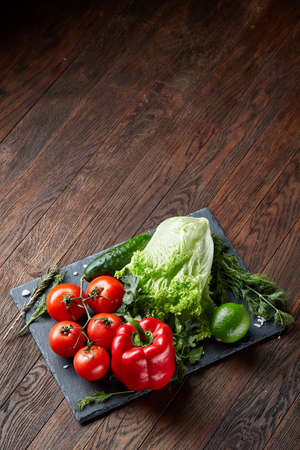 Vegetarian still life of assorted fresh vegetables and herbs on vintage wooden background, top view, selective focus.の写真素材