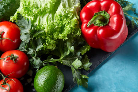 Close-up still life of assorted fresh vegetables and herbs on blue background, top view, selective focus.の写真素材