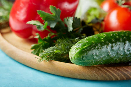 Refreshing close-up still life of assorted fresh vegetables and herbs on blue background, top view, selective focus.の写真素材