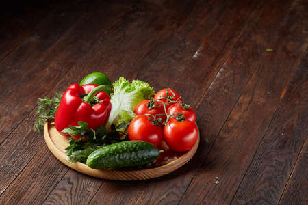 Close-up still life of assorted fresh vegetables and herbs on vintage wooden background, top view, selective focus.の写真素材