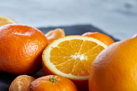 Close-up of whole and half cut fresh tangerine and orange on cutting board over white background, shallow depth of fieldの写真素材